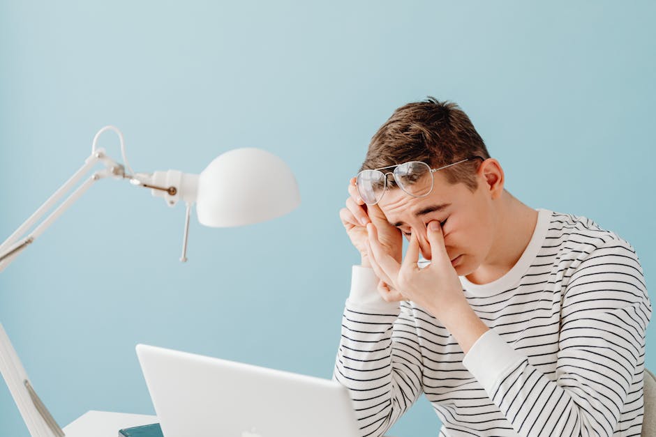 tired woman rubbing eyes while working at computer screen showing digital eye strain